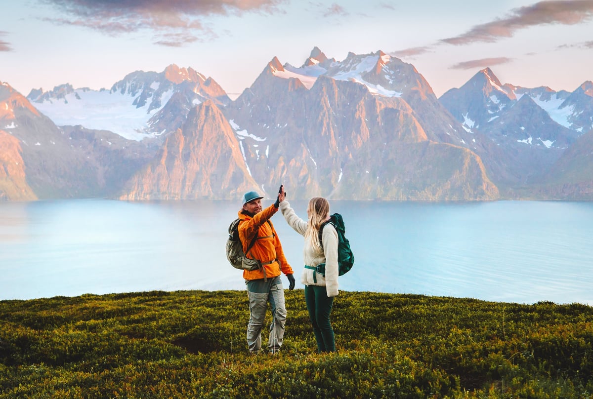 Couple friends high five on mountain top backpackers traveling together