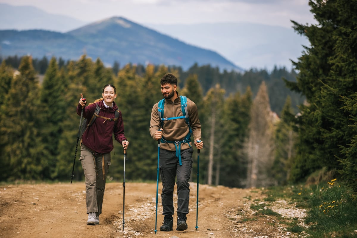 A young man and woman hiking through a scenic mountain forest with backpacks