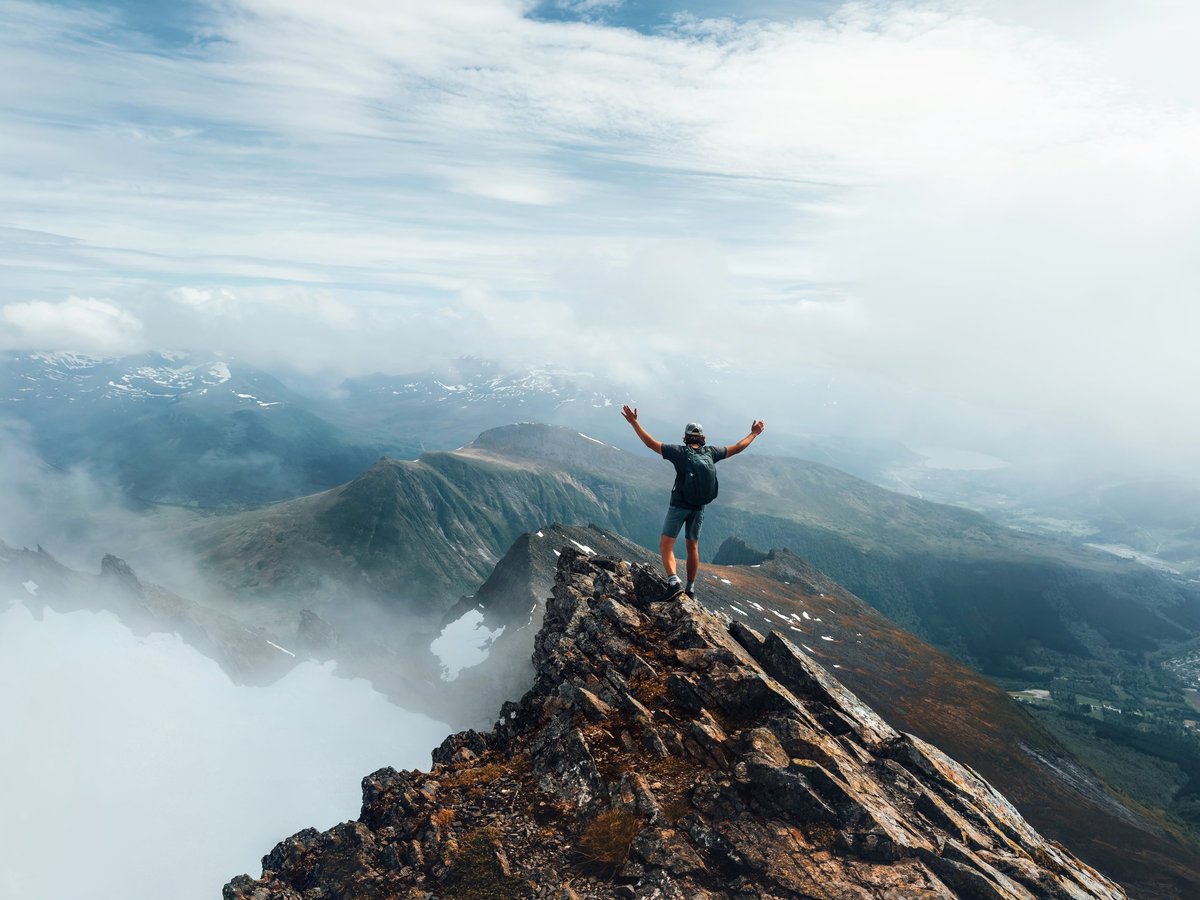 Man climber standing on mountain summit in Norway travel climbing vacations adventure