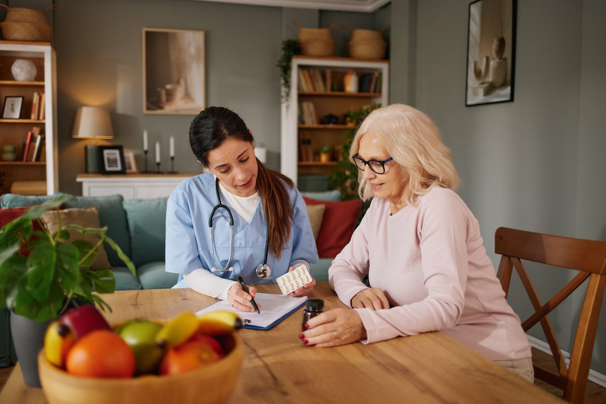 Nurse discussing medication with an elderly patient during a home visit